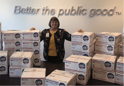 Patriot Package Coordinator Pam Gray smiles with packages before they are shipped overseas